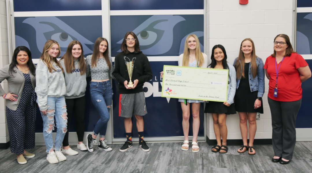 Group of students holding a larger check donation from Teens in the Drivers Seat organization